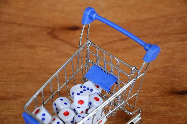 Oyuncak alışveriş arabasındaki beyaz zarlar ahşap dokuda. 