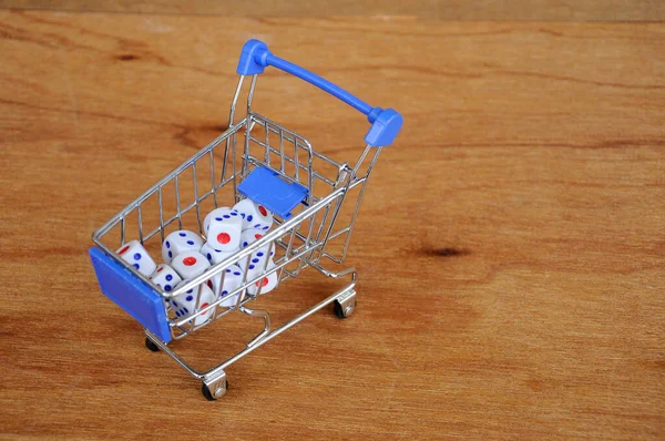 Oyuncak alışveriş arabasındaki beyaz zarlar ahşap dokuda. 