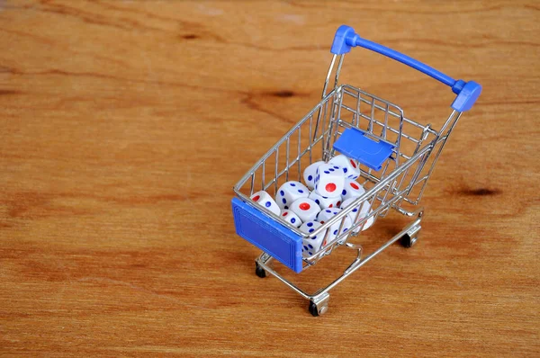 Oyuncak alışveriş arabasındaki beyaz zarlar ahşap dokuda. 