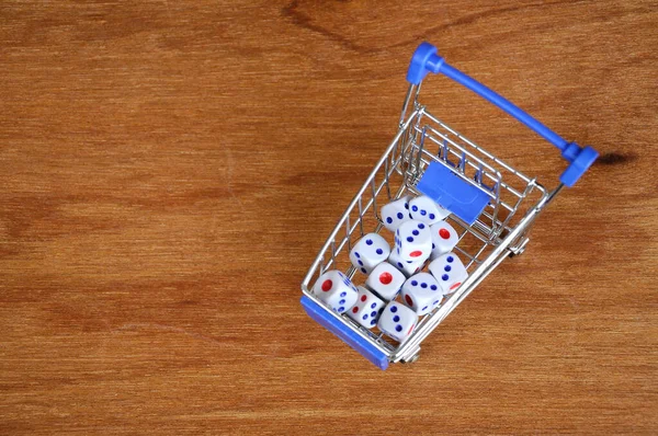 Oyuncak alışveriş arabasındaki beyaz zarlar ahşap dokuda. 