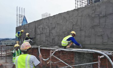 JASIN, MALAYSIA -14 HAZİRAN 2017: Malezya 'nın Jasin kentindeki inşaat sahasında çimento ve kum karışımı kullanarak inşaat duvarlarını ve kirişleri alçılayan inşaat işçileri