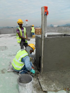 JASIN, MALAYSIA -14 HAZİRAN 2017: Malezya 'nın Jasin kentindeki inşaat sahasında çimento ve kum karışımı kullanarak inşaat duvarlarını ve kirişleri alçılayan inşaat işçileri
