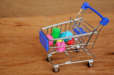 Oyuncak alışveriş vagonunun içindeki tahta desenli plastik küp ve diğer şekillerle dolu.. 