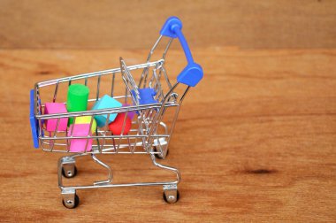 Oyuncak alışveriş vagonunun içindeki tahta desenli plastik küp ve diğer şekillerle dolu.. 