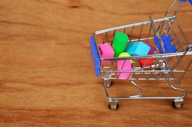 Oyuncak alışveriş vagonunun içindeki tahta desenli plastik küp ve diğer şekillerle dolu.. 