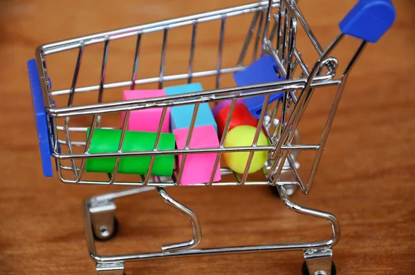 Oyuncak alışveriş vagonunun içindeki tahta desenli plastik küp ve diğer şekillerle dolu.. 