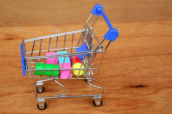 Oyuncak alışveriş vagonunun içindeki tahta desenli plastik küp ve diğer şekillerle dolu.. 