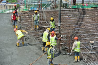 PERAK, MALAYSIA - SEPTEMBER 05, 2016: İnşaat işçileri inşaat alanındaki vinç veya beton vinç hortumuyla zemine ıslak beton dökerek yer kaplama çalışması yapıyorlar.