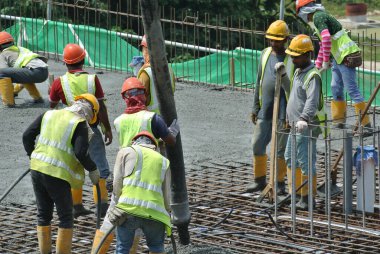 PERAK, MALAYSIA - SEPTEMBER 05, 2016: İnşaat işçileri inşaat alanındaki vinç veya beton vinç hortumuyla zemine ıslak beton dökerek yer kaplama çalışması yapıyorlar.
