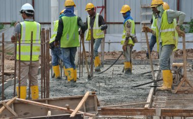 SELANGOR, MALAYSIA -18 Haziran 2016: İnşaat işçileri inşaat alanında beton vibratör kullanarak form çalışma formuna dökülen beton çamuru sıkıştırdılar. 