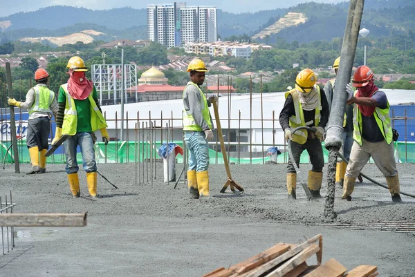 PERAK, MALAYSIA - SEPTEMBER 05, 2016: İnşaat işçileri inşaat alanındaki vinç veya beton vinç hortumuyla zemine ıslak beton dökerek yer kaplama çalışması yapıyorlar.