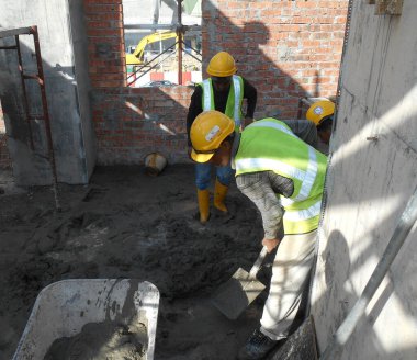 MALACCA, MALAYSIA -24 AĞUSTOS: İnşaat işçileri tuğla ve sıva işi için harç oluşturmak amacıyla çimento, kum ve suyu elle karıştırıyorlar. 