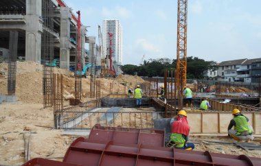 SELANGOR, MALAYSIA - 22 Nisan 2021: Bir grup inşaat işçisi bir şantiyede çalışıyor. Onlara gerekli güvenlik donanımı sağlandı. İnşaat alanındaki ilerleme tam gaz devam ediyor..