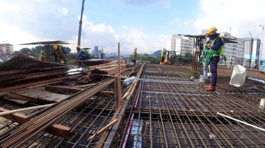 SELANGOR, MALAYSIA - 22 Nisan 2021: Bir grup inşaat işçisi bir şantiyede çalışıyor. Onlara gerekli güvenlik donanımı sağlandı. İnşaat alanındaki ilerleme tam gaz devam ediyor..