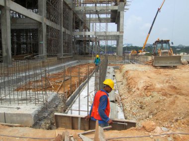 SELANGOR, MALAYSIA - 22 Nisan 2021: Bir grup inşaat işçisi bir şantiyede çalışıyor. Onlara gerekli güvenlik donanımı sağlandı. İnşaat alanındaki ilerleme tam gaz devam ediyor..