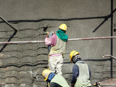 SELANGOR, MALAYSIA -MARCH 4: Construction workers are spraying liquid concrete onto the slope surface to form a retaining wall layer. It acts to prevent erosion on the slope surface.
