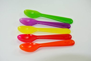 Beyaz zemin üzerinde renkli plastik kaşıklar ve çatallar