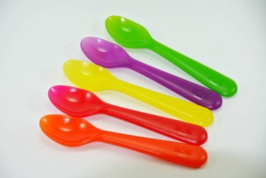 Beyaz zemin üzerinde renkli plastik kaşıklar ve çatallar