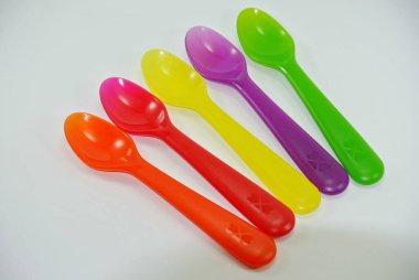 Beyaz zemin üzerinde renkli plastik kaşıklar ve çatallar