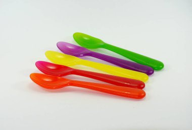 Beyaz zemin üzerinde renkli plastik kaşıklar ve çatallar