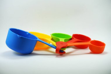 Beyaz arkaplanda farklı hacme sahip renkli ölçü kabı. 