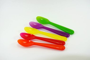Beyaz zemin üzerinde renkli plastik kaşıklar ve çatallar