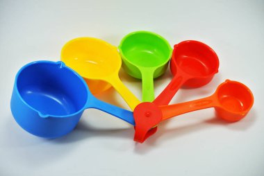 Beyaz arkaplanda farklı hacme sahip renkli ölçü kabı. 