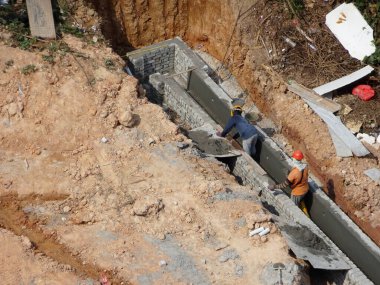 SELANGOR, MALAYSIA - 6 Temmuz 2021: İnşaat işçileri bir inşaat sahasında günlük rutin işleri ve temizlik işlerini yürütüyorlar. Bölgede güvenlik ekipmanı giymeleri gerekiyor..