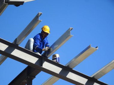 SELANGOR, MALAYSIA -16 Haziran 2021: İnşaat işçileri inşaat sahalarına kiriş ve çatı örtüleri kurar. Kullanılan hafif çatı kirişleri daha ekonomik, sağlam ve hızlıdır.