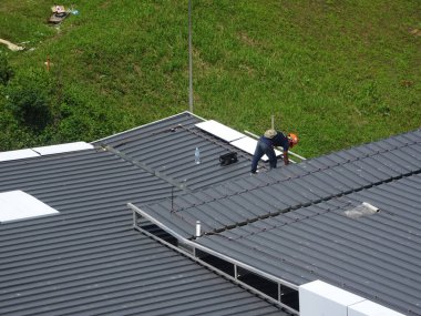SELANGOR, MALAYSIA -JUNE 16, 2021: Construction workers install trusses and roofing sheets at construction sites. Lightweight roof trusses used are more economical, sturdy and fast.