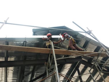 SELANGOR, MALAYSIA -16 Haziran 2021: İnşaat işçileri inşaat sahalarına kiriş ve çatı örtüleri kurar. Kullanılan hafif çatı kirişleri daha ekonomik, sağlam ve hızlıdır.