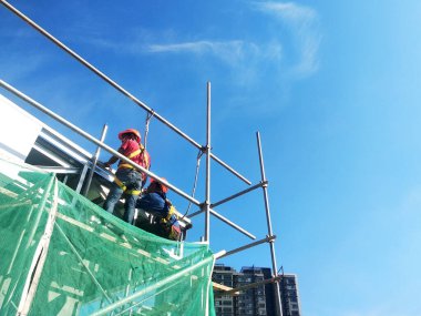SELANGOR, MALAYSIA -JUNE 16, 2021: Construction workers install trusses and roofing sheets at construction sites. Lightweight roof trusses used are more economical, sturdy and fast.