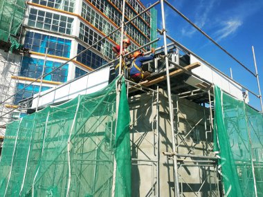 SELANGOR, MALAYSIA -JUNE 16, 2021: Construction workers install trusses and roofing sheets at construction sites. Lightweight roof trusses used are more economical, sturdy and fast.