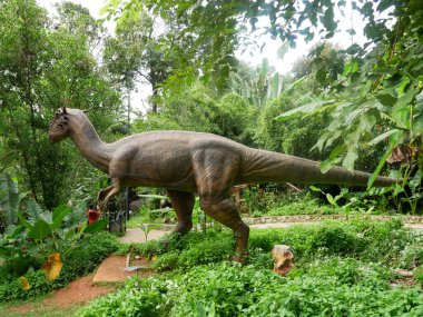 MELAKA, MALAYSIA - JUNE 6, 2022: Replicas of various types of dinosaurs built to life size. It is decorated with tropical plants to make it seem alive.