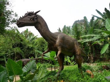 MELAKA, MALAYSIA - JUNE 6, 2022: Replicas of various types of dinosaurs built to life size. It is decorated with tropical plants to make it seem alive.