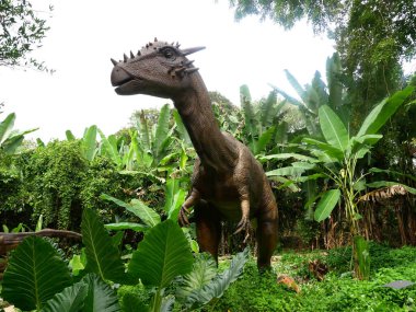 MELAKA, MALAYSIA - JUNE 6, 2022: Replicas of various types of dinosaurs built to life size. It is decorated with tropical plants to make it seem alive.