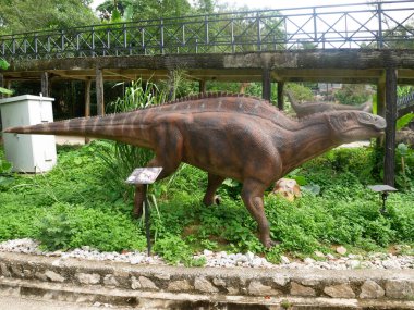 MELAKA, MALAYSIA - JUNE 6, 2022: Replicas of various types of dinosaurs built to life size. It is decorated with tropical plants to make it seem alive.