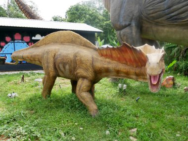 MELAKA, MALAYSIA - JUNE 6, 2022: Replicas of various types of dinosaurs built to life size. It is decorated with tropical plants to make it seem alive.