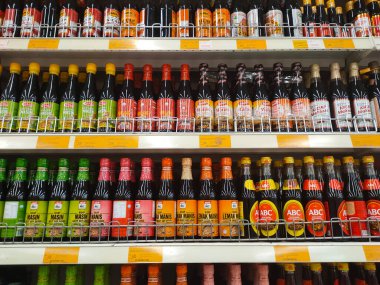 MELAKA, MALAYSIA - MARCH 4, 2022: Salty and sweet soy sauce bottled in glass bottles and displayed for sale. Labeled by brand and has a price tag. Separated by brand.