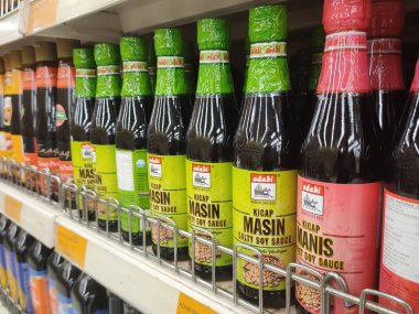 MELAKA, MALAYSIA - MARCH 4, 2022: Salty and sweet soy sauce bottled in glass bottles and displayed for sale. Labeled by brand and has a price tag. Separated by brand.