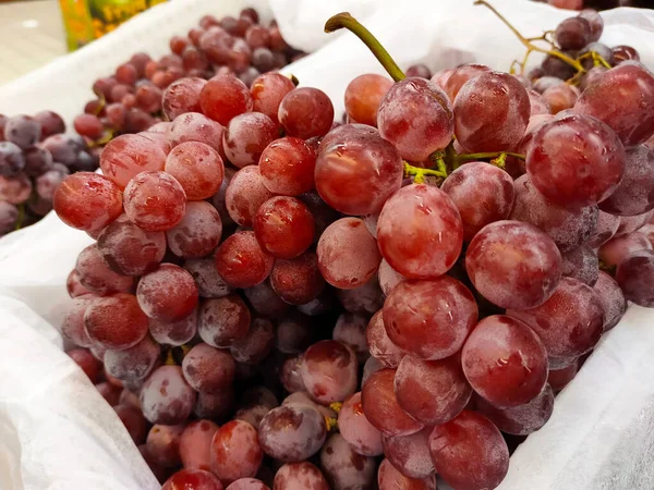 Fresh grapes are displayed for sale in the market. Just taken out of the fridge and the frosting is still visible.