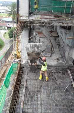 JOHOR, MALAYSIA -JANUARY 16. 2017: Group of construction workers pouring wet concrete using concrete bucket into the timber form work at the construction site.  