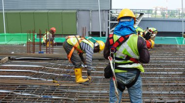MALACCA, MALAYSIA -JULY 23, 2016: Construction workers wearing safety harness belt at other safety gear during working at the construction site area.  