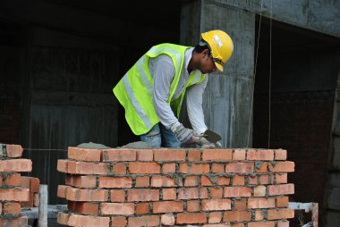 JOHOR, MALAYSIA -AĞUSTOS 05, 2016: İnşaat alanında inşaat duvarları oluşturmak için tuğla döşeyen tuğla ustası. 