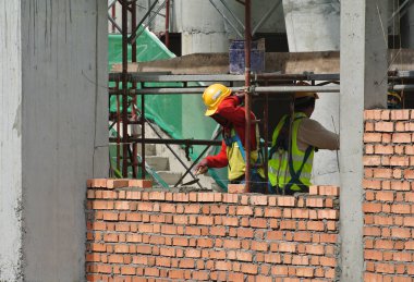 JOHOR, MALAYSIA -AĞUSTOS 05, 2016: İnşaat alanında inşaat duvarları oluşturmak için tuğla döşeyen tuğla ustası. 