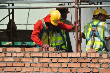 JOHOR, MALAYSIA -AĞUSTOS 05, 2016: İnşaat alanında inşaat duvarları oluşturmak için tuğla döşeyen tuğla ustası. 