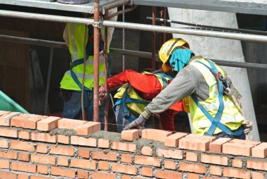 JOHOR, MALAYSIA -AĞUSTOS 05, 2016: İnşaat alanında inşaat duvarları oluşturmak için tuğla döşeyen tuğla ustası. 