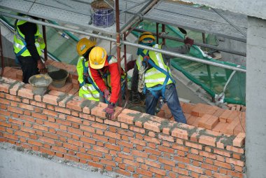 JOHOR, MALAYSIA -AĞUSTOS 05, 2016: İnşaat alanında inşaat duvarları oluşturmak için tuğla döşeyen tuğla ustası. 