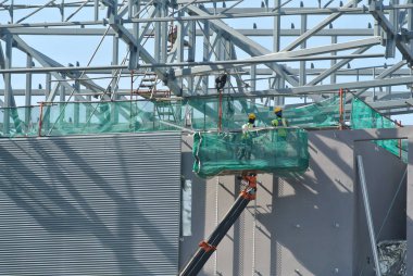 JOHOR, MALAYSIA -MAY 15, 2016: Construction workers standing in the skylift bucket while working at high level in the construction site in Malaysia. 
