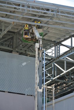 JOHOR, MALAYSIA -MAY 15, 2016: Construction workers standing in the skylift bucket while working at high level in the construction site in Malaysia. 